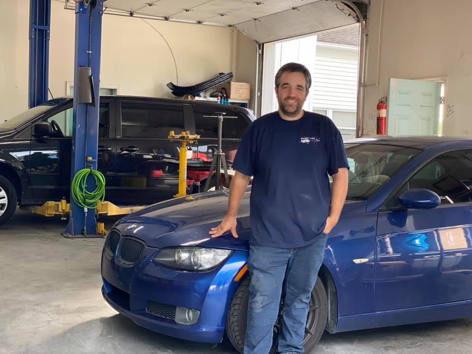 Freedom Auto Care technician standing beside a vehicle in the shop